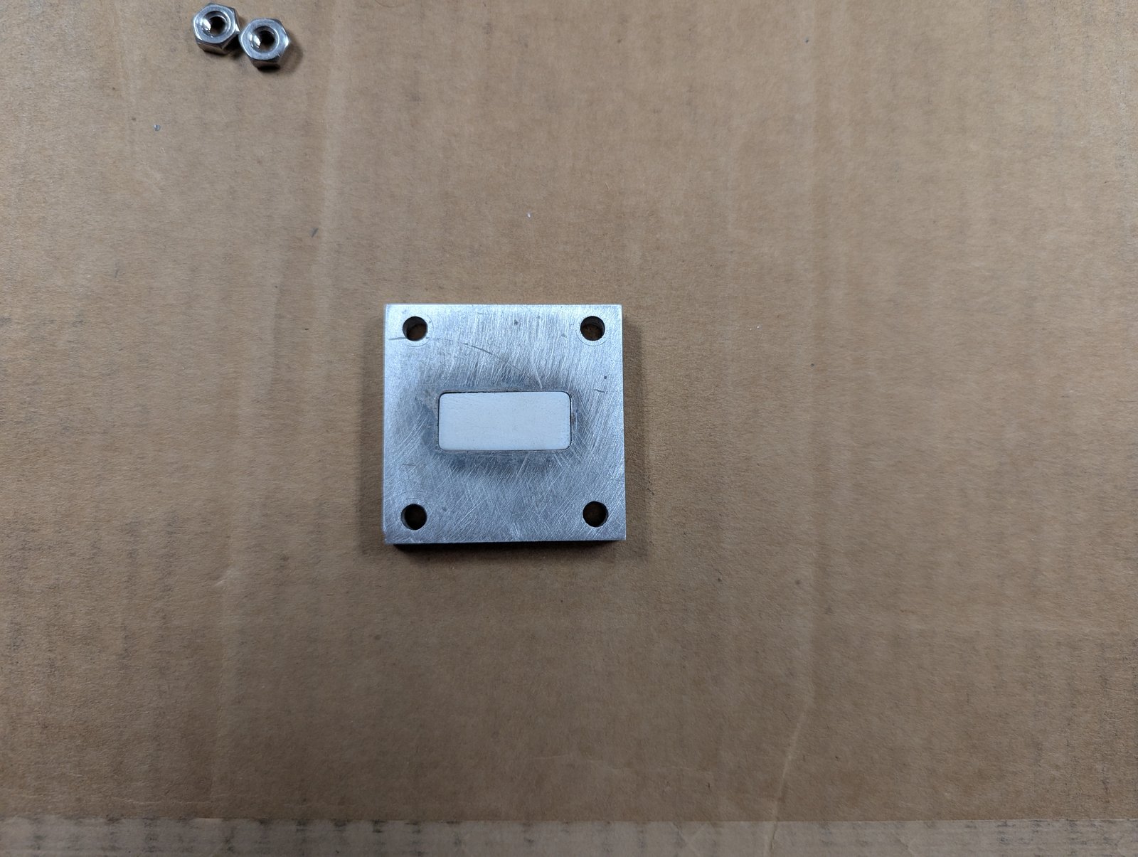 Material sample fitted into the opening of a flange-sized sample holder plate